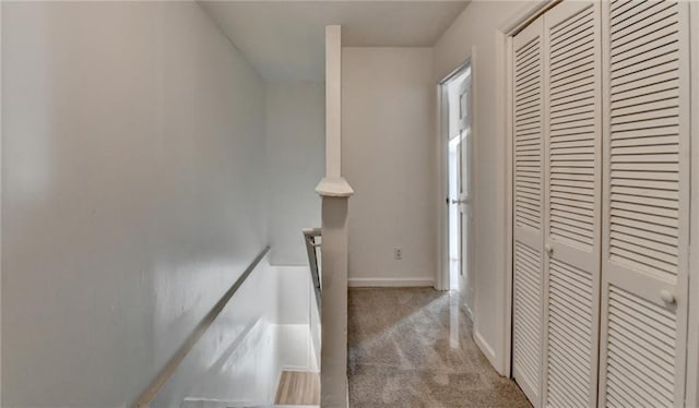 hallway featuring baseboards, light colored carpet, and an upstairs landing