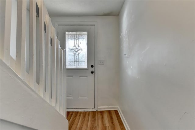 doorway featuring baseboards and wood finished floors