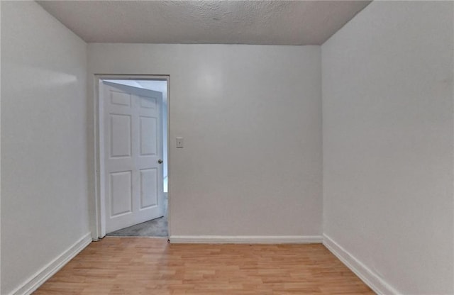 unfurnished room with light wood-style floors, a textured ceiling, and baseboards