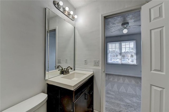 bathroom with a textured ceiling, vanity, toilet, and a ceiling fan