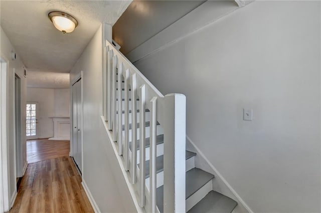 staircase with baseboards and wood finished floors