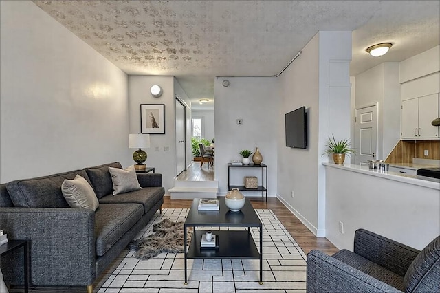 living area featuring light wood-type flooring, baseboards, and a textured ceiling