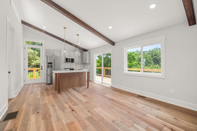 kitchen featuring lofted ceiling with beams, stainless steel appliances, visible vents, light countertops, and light wood-type flooring