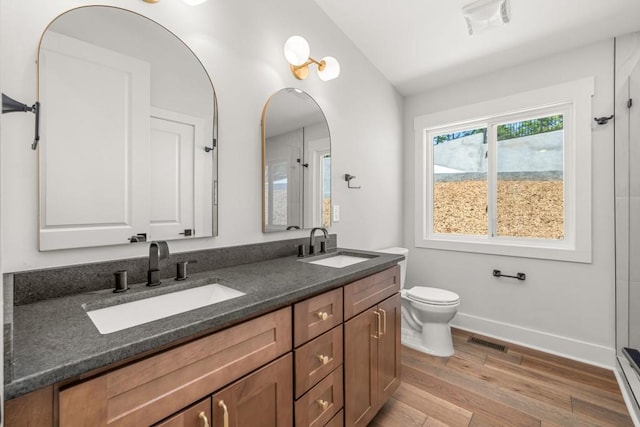 6564 Bermuda Ln, Flowery Branch, GA 30542 - bathroom with wood finished floors, toilet, double vanity, baseboards, and vaulted ceiling