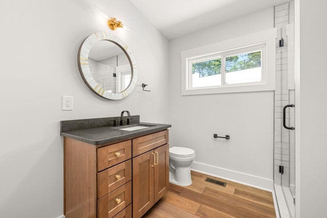 bathroom with a stall shower, baseboards, visible vents, wood finished floors, and vanity