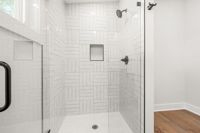 bathroom featuring a stall shower, baseboards, and wood finished floors