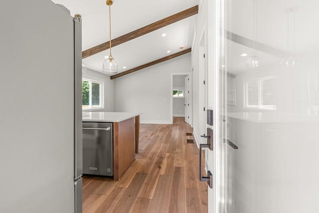 kitchen with stainless steel appliances, light countertops, hanging light fixtures, light wood-style flooring, and lofted ceiling with beams