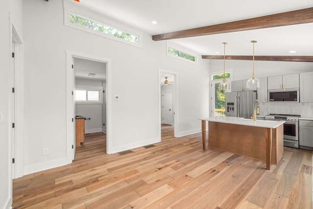 kitchen with stainless steel appliances, beam ceiling, light countertops, and light wood finished floors