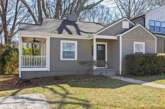 view of front of house featuring covered porch, a shingled roof, crawl space, a front lawn, and a chimney