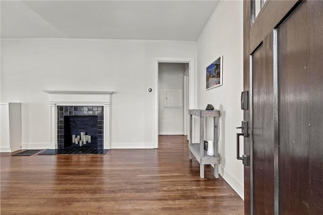 interior space featuring baseboards, a fireplace, wood finished floors, and crown molding