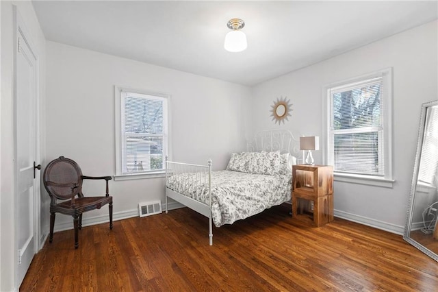 bedroom with multiple windows, baseboards, and wood finished floors