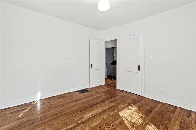 spare room featuring visible vents, baseboards, and wood finished floors