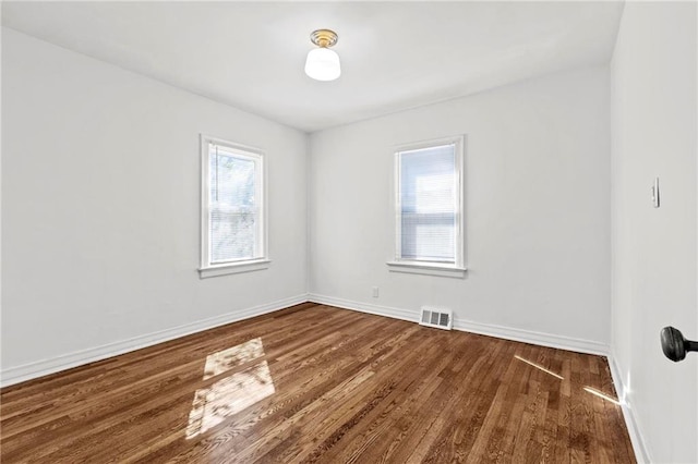 unfurnished room with wood finished floors, visible vents, and baseboards