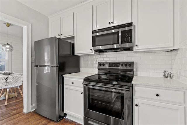 kitchen with light countertops, appliances with stainless steel finishes, wood finished floors, and white cabinets