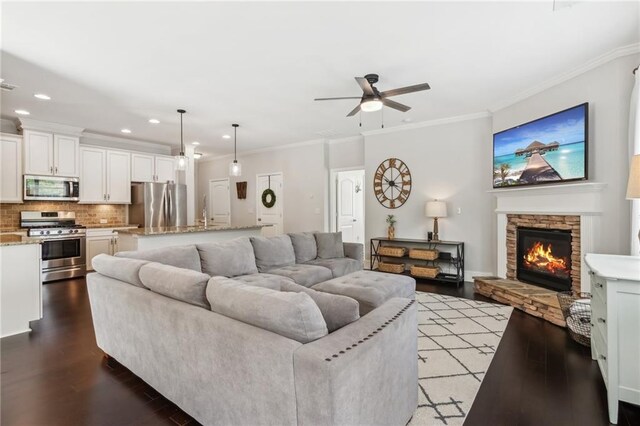 4020 Huron Dr, Cumming, GA 30028 - living area featuring wood finished floors, ceiling fan, a chandelier, crown molding, and a stone fireplace