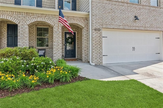 4020 Huron Dr, Cumming, GA 30028 - view of exterior entry with driveway, brick siding, a porch, and a garage