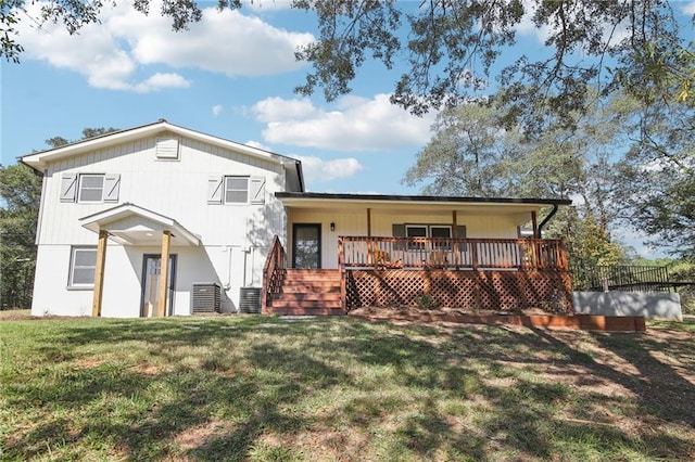 rear view of house with central AC unit, a wooden deck, and a yard