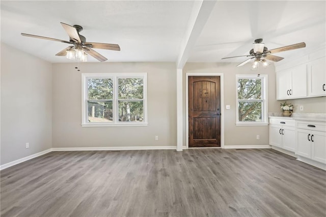 interior space featuring ceiling fan, white cabinets, light hardwood / wood-style flooring, and beam ceiling