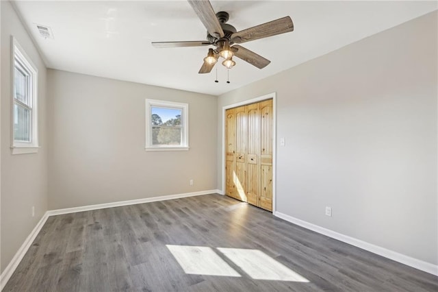 unfurnished bedroom featuring dark wood-type flooring, a closet, and ceiling fan