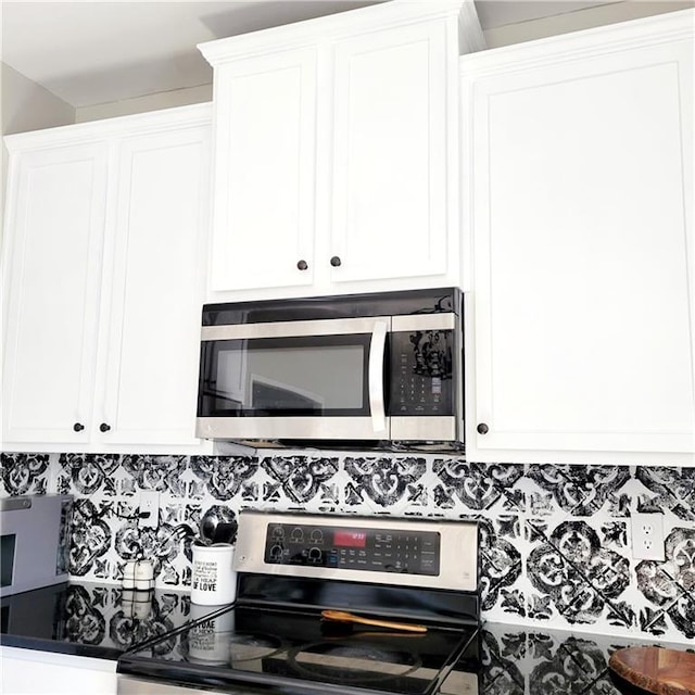 kitchen with decorative backsplash, stove, and white cabinets