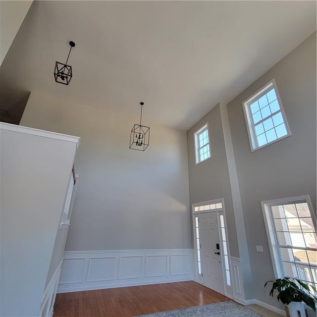 foyer with a towering ceiling, wood-type flooring, and a notable chandelier