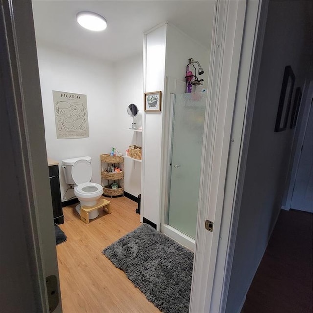 bathroom with toilet, an enclosed shower, and hardwood / wood-style flooring