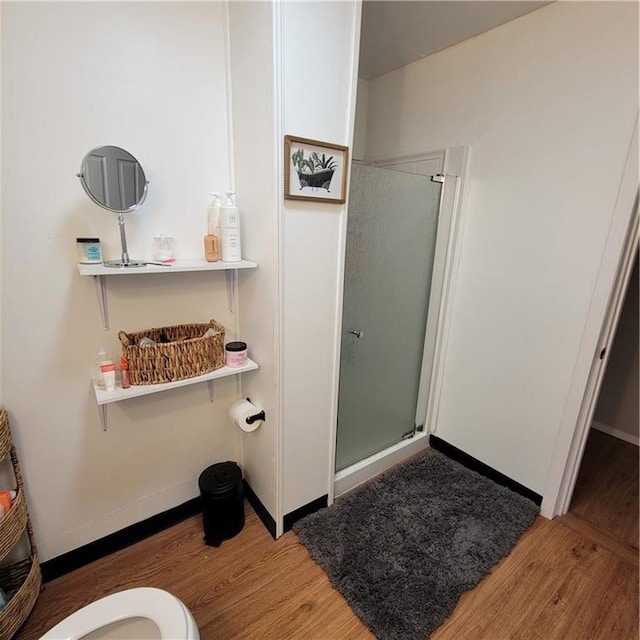 bathroom featuring toilet, a shower with door, and hardwood / wood-style flooring