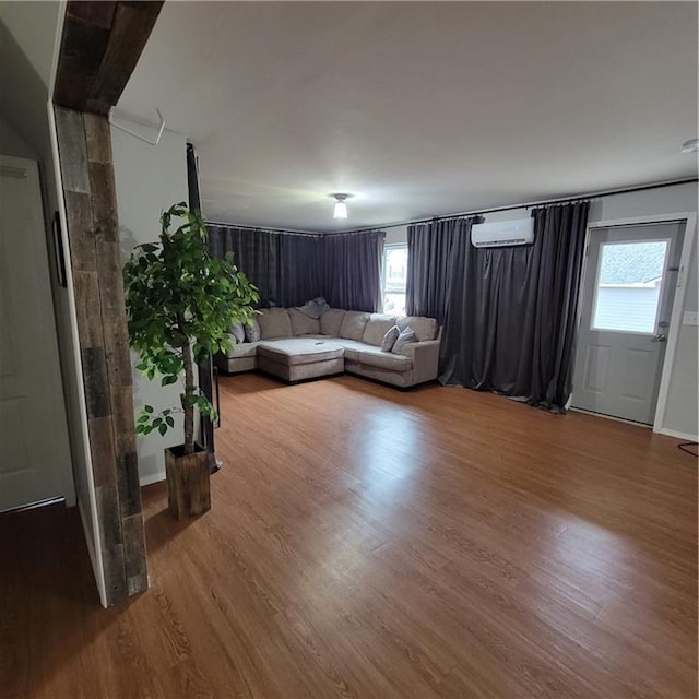 unfurnished living room with wood-type flooring and a wall mounted air conditioner