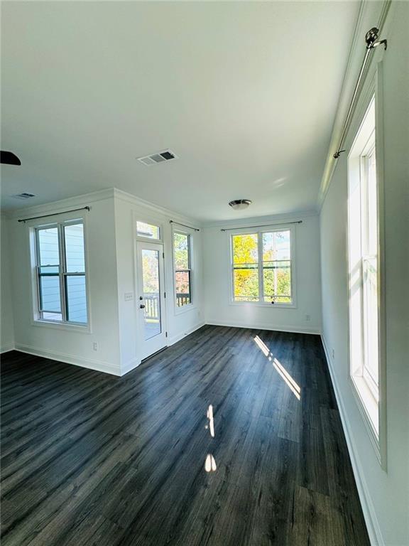 unfurnished living room with crown molding and dark hardwood / wood-style flooring