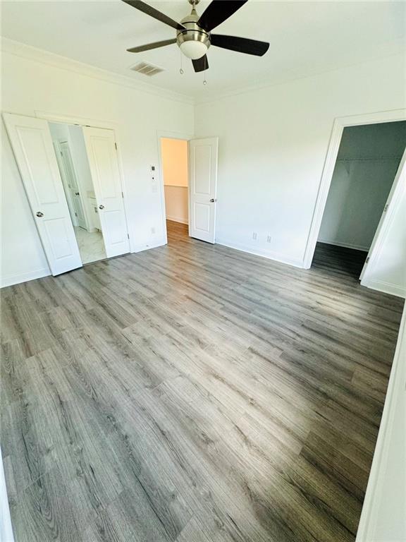 unfurnished bedroom with light hardwood / wood-style floors, crown molding, a closet, and ceiling fan