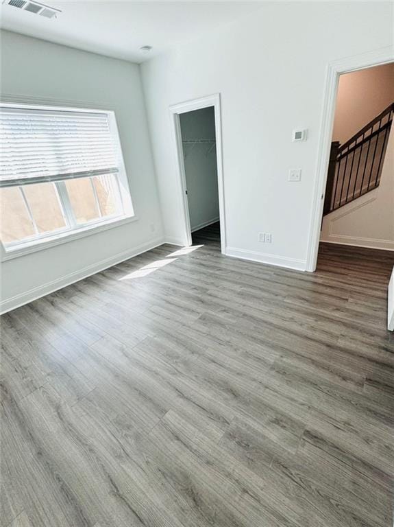 unfurnished room with stairs, wood finished floors, visible vents, and baseboards