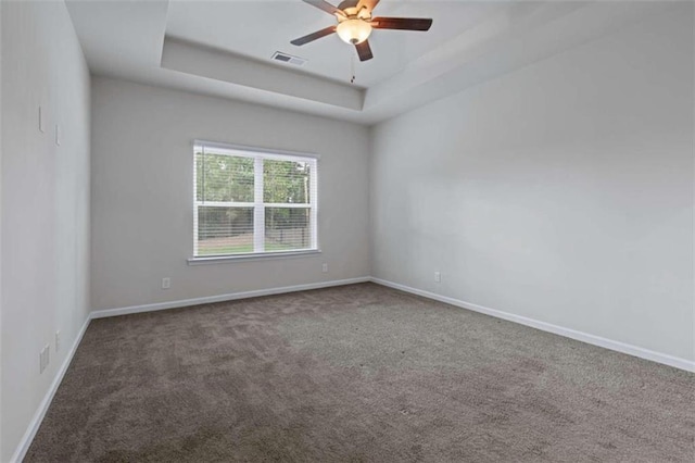 carpeted spare room with ceiling fan and a raised ceiling