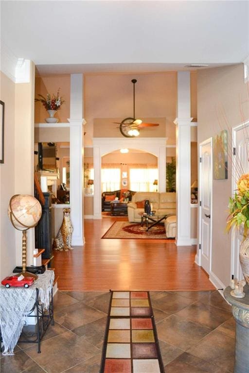 interior space featuring decorative columns, ceiling fan, and dark hardwood / wood-style floors