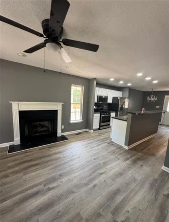 unfurnished living room with ceiling fan, a textured ceiling, and hardwood / wood-style flooring