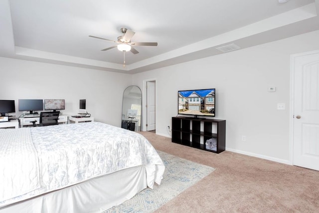 carpeted bedroom featuring a raised ceiling and ceiling fan