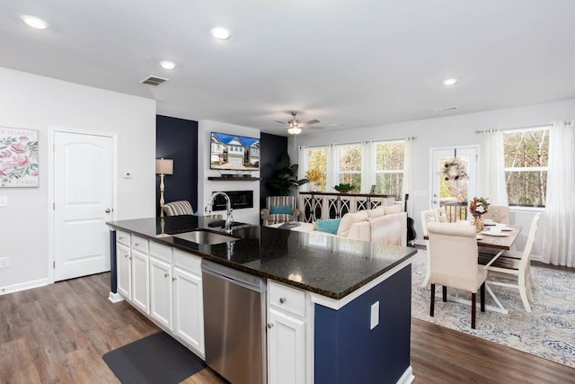 kitchen featuring stainless steel dishwasher, a healthy amount of sunlight, sink, white cabinetry, and an island with sink