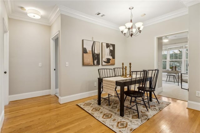 dining area featuring crown molding, a notable chandelier, visible vents, light wood-type flooring, and baseboards