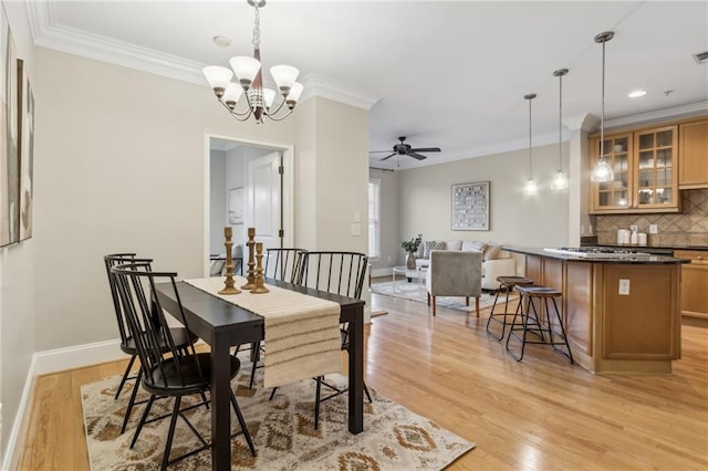 dining area featuring baseboards, crown molding, and light wood finished floors