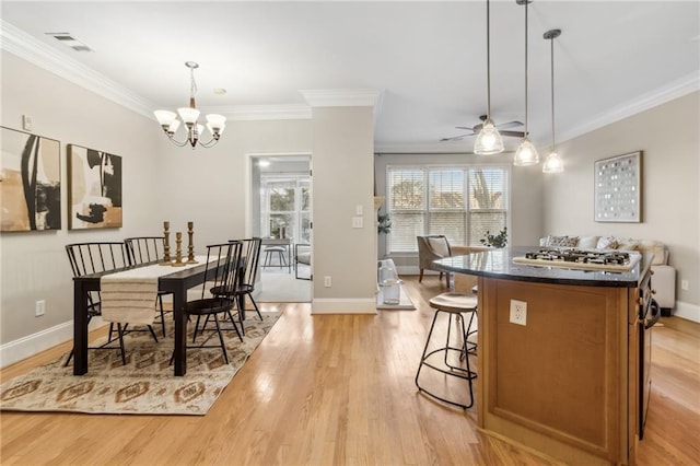 dining space featuring light wood-style floors, baseboards, visible vents, and ornamental molding