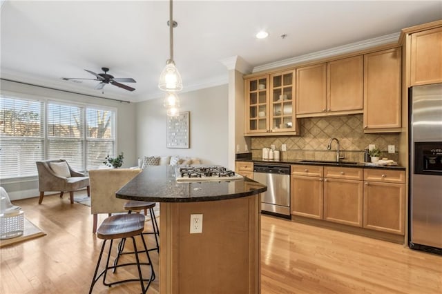 kitchen with a breakfast bar area, ornamental molding, a center island, stainless steel appliances, and a sink