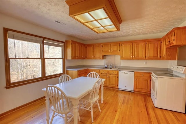 kitchen with sink, white appliances, a textured ceiling, and light hardwood / wood-style floors