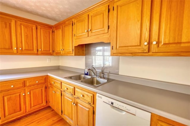 kitchen featuring white dishwasher, sink, a textured ceiling, and light hardwood / wood-style floors