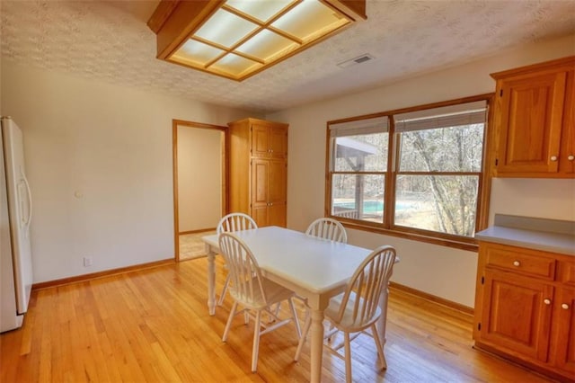 dining room with a textured ceiling and light hardwood / wood-style flooring