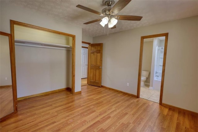 unfurnished bedroom featuring ceiling fan, connected bathroom, light wood-type flooring, a closet, and a textured ceiling