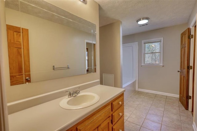 bathroom featuring a tub, a textured ceiling, tile patterned floors, and vanity