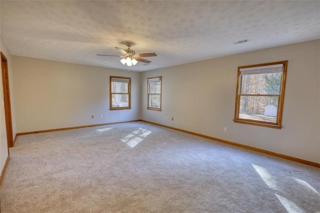 empty room with light carpet, ceiling fan, and a wealth of natural light