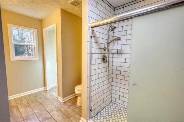 bathroom featuring toilet, a textured ceiling, and an enclosed shower