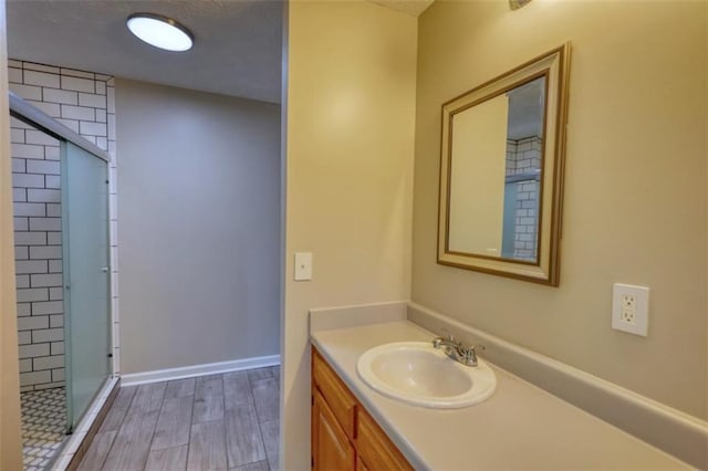 bathroom featuring a shower with shower door and vanity