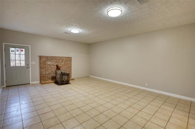 unfurnished living room with a textured ceiling, light tile patterned flooring, and a wood stove