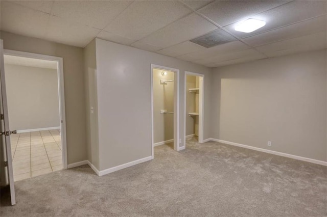 interior space with a drop ceiling, a closet, and light carpet